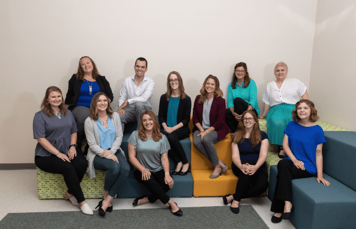 team of music therapists sitting on colorful sofas and smiling at the camera.