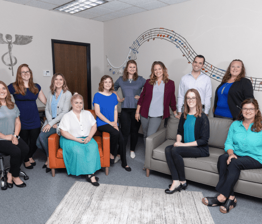 team of therapists smiling and seated on colorful couches