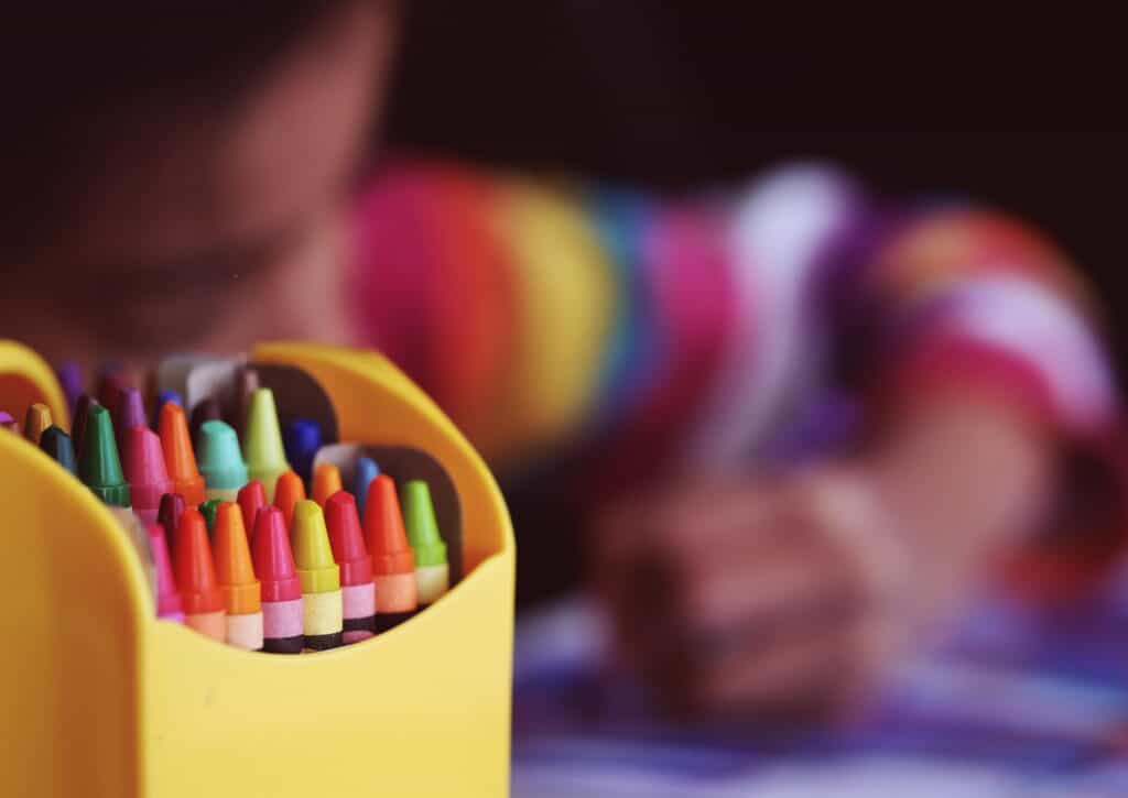 A child coloring in the background with a set of crayons in the foreground. Music therapy websites Harmony healing 