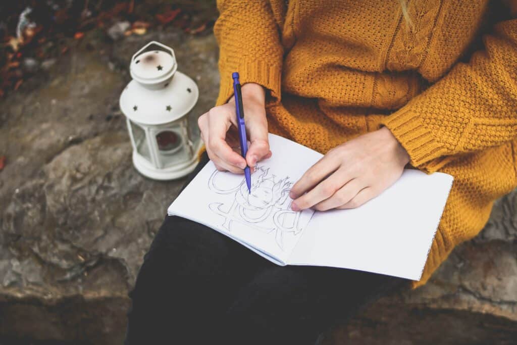 A woman using art to express herself. She is drawing in a notebook. H h music Dynamic music therapy 