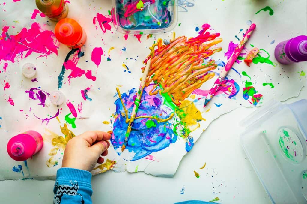 a small child's hand finger painting with vibrant colors. Healing harmonies Music therapy website